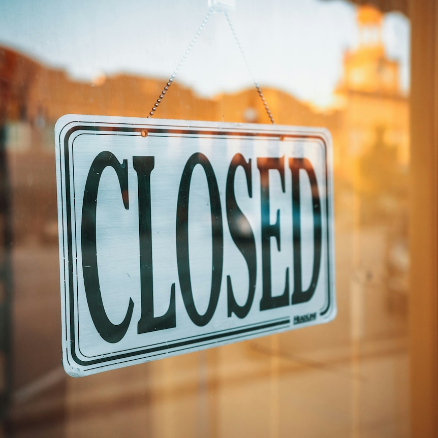 closed sign hangs on the inside of business's glass door