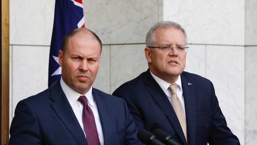 Josh Frydenberg and Scott Morrison stand in a court yard at podia with an australian flag behind them