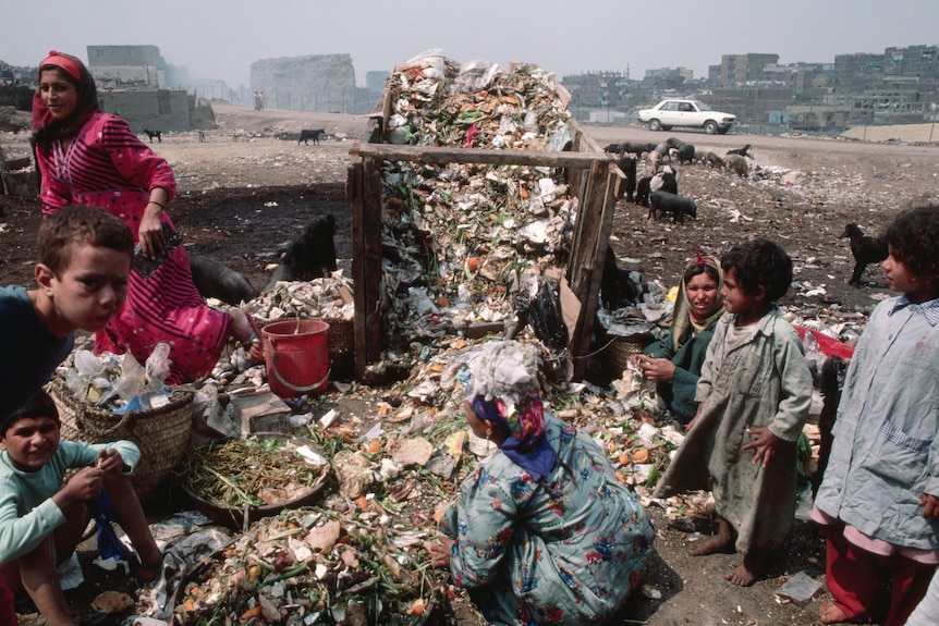 Children surround a wooden crate filled with garbage 