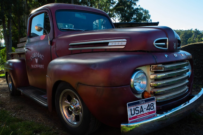 A stylish, heavy-bodied vintage pick-up truck, tightly framed, original dark red paint.