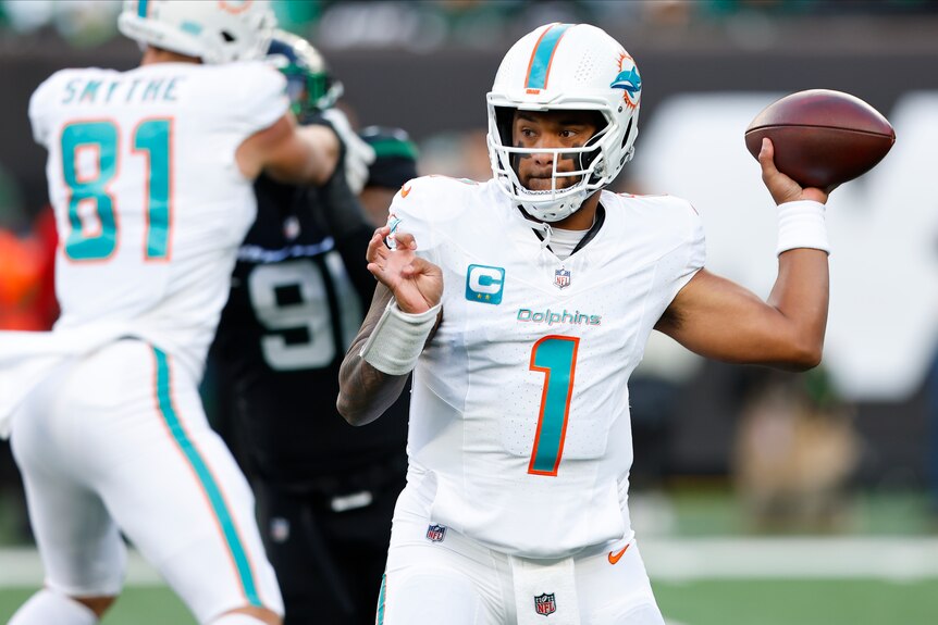 A Miami NFL quarterback looks downfield as he cocks his arm ready to pass the ball during a game. 