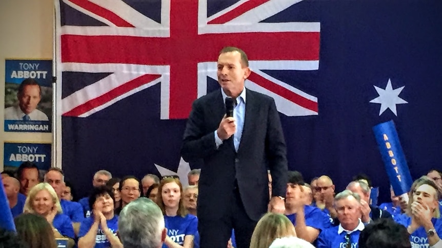Tony Abbott in front of an Australian flag.