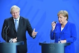 Germany's Chancellor Angela Merkel and British Prime Minister Boris Johnson stand at podiums next to each other.