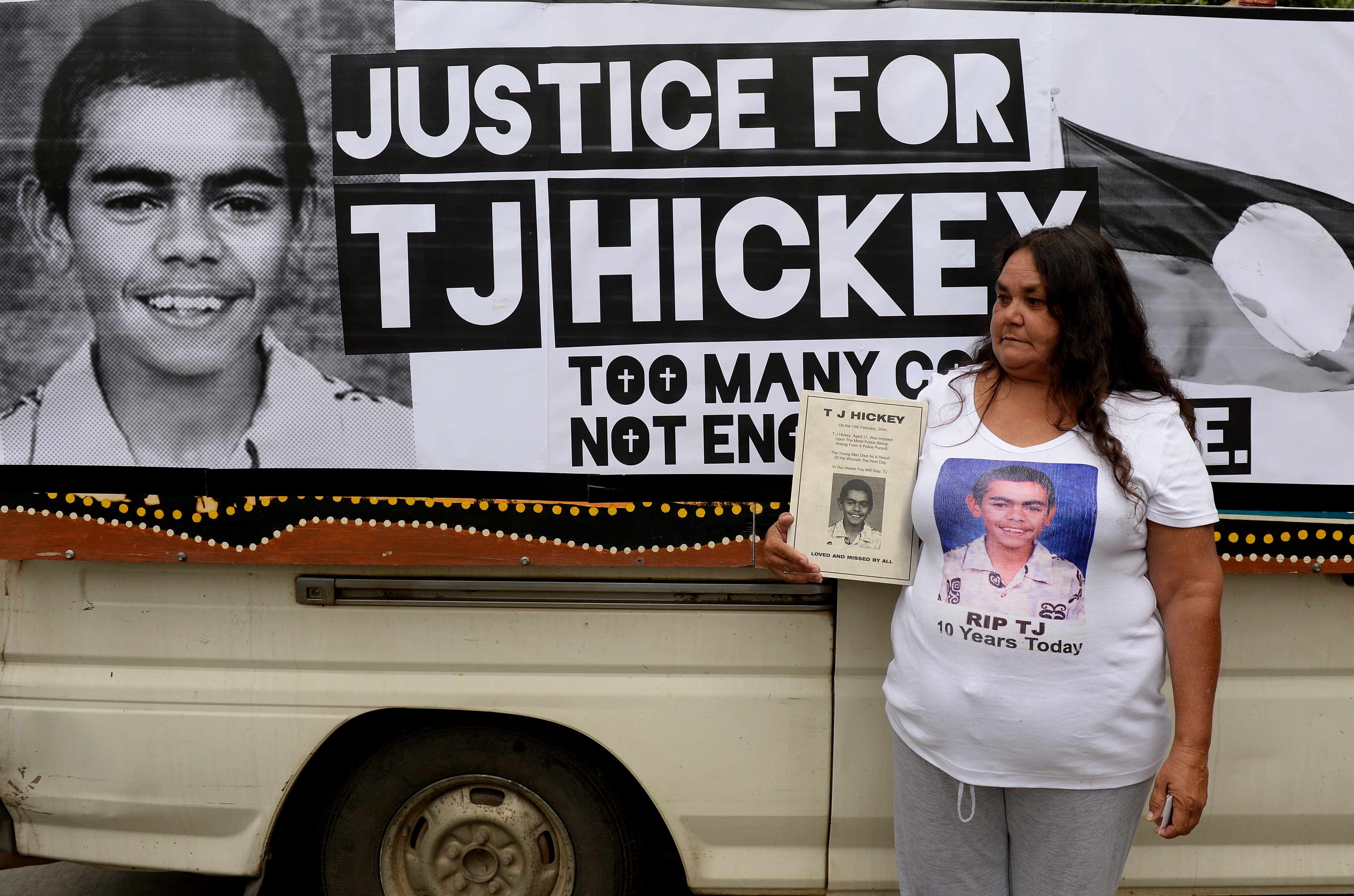 A woman is standing in front of a sign of a black adn white photo of an Aboriginal boy