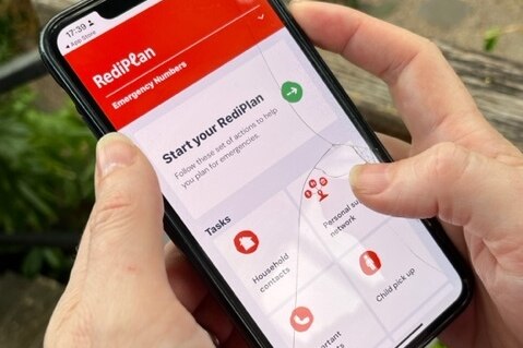 A hand holds a mobile phone with the Get Ready App on the screen