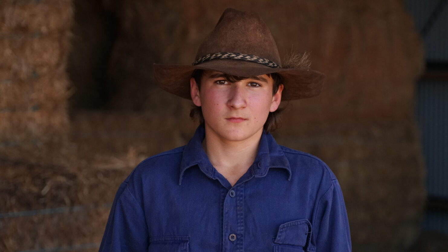 Boy with cowboy hat looks pensive. 