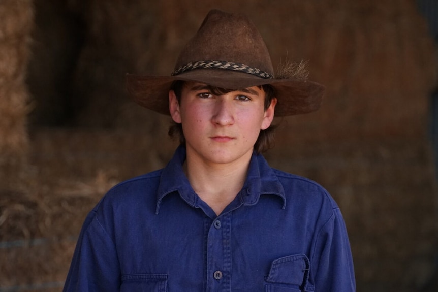Boy with cowboy hat looks pensive. 