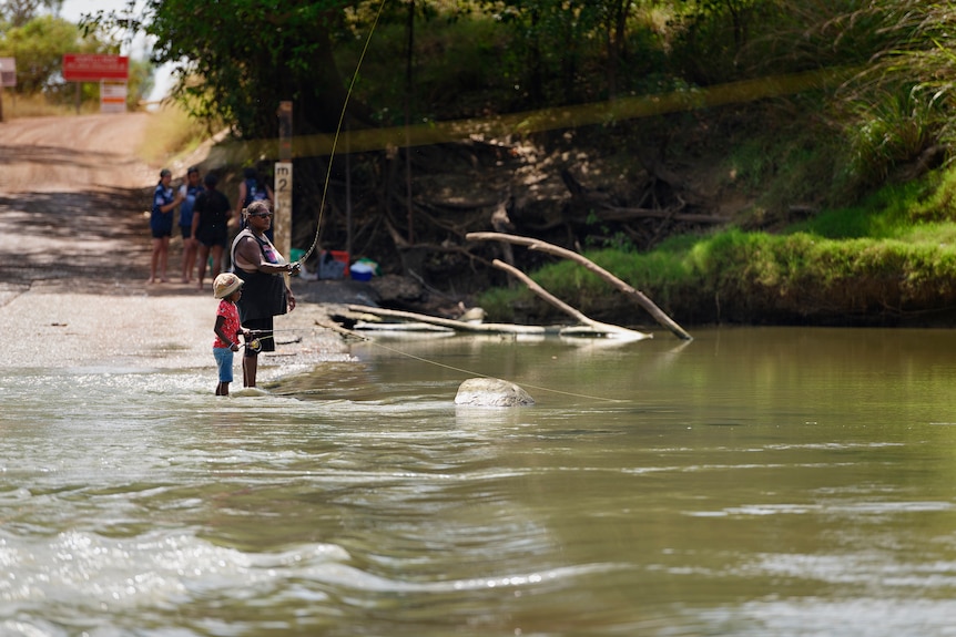 A woman and a girl fish in the shallow water at Cahill's crossing.