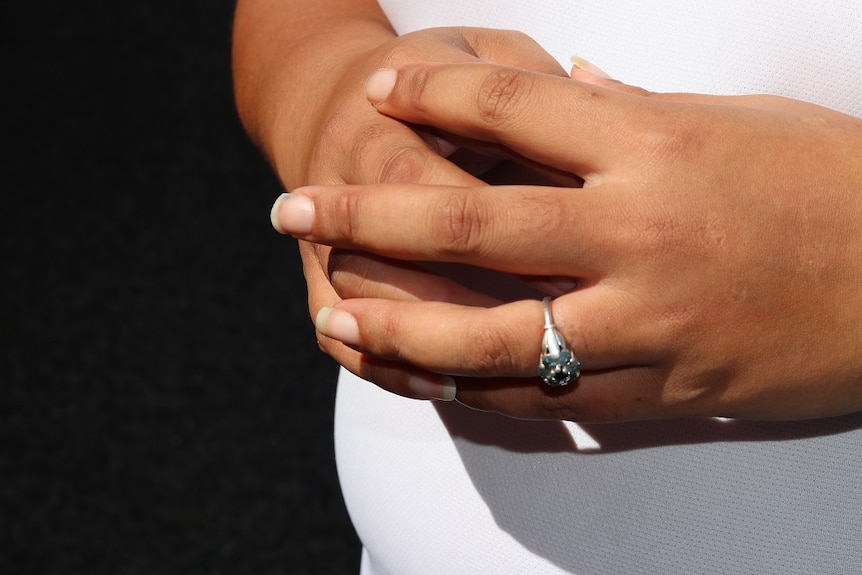 A woman's clasped hands with a ring