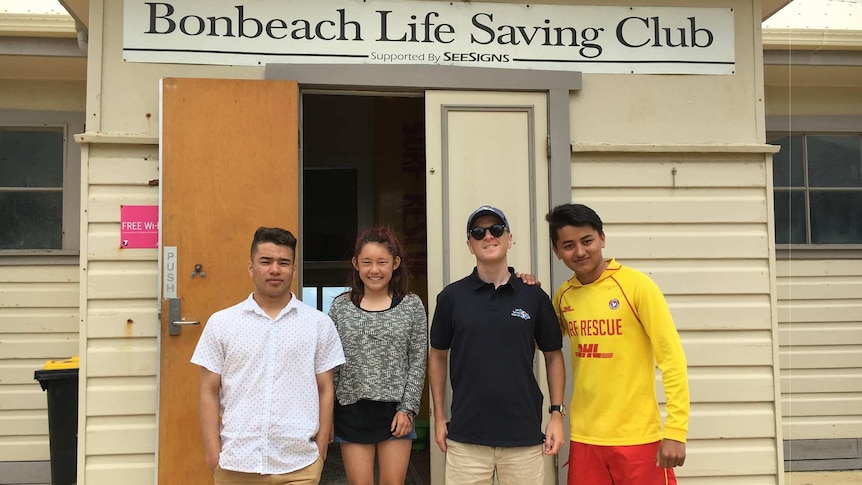 Four young trainees from migrant backgrounds pose in front of the Bonbeach Life Saving Club
