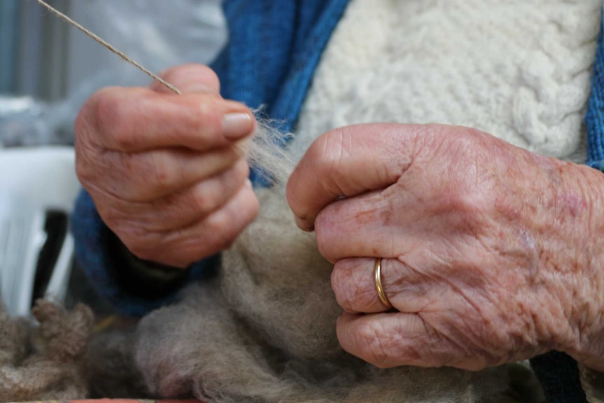 A close up of Isabel Black's hands in the process of spinning wool