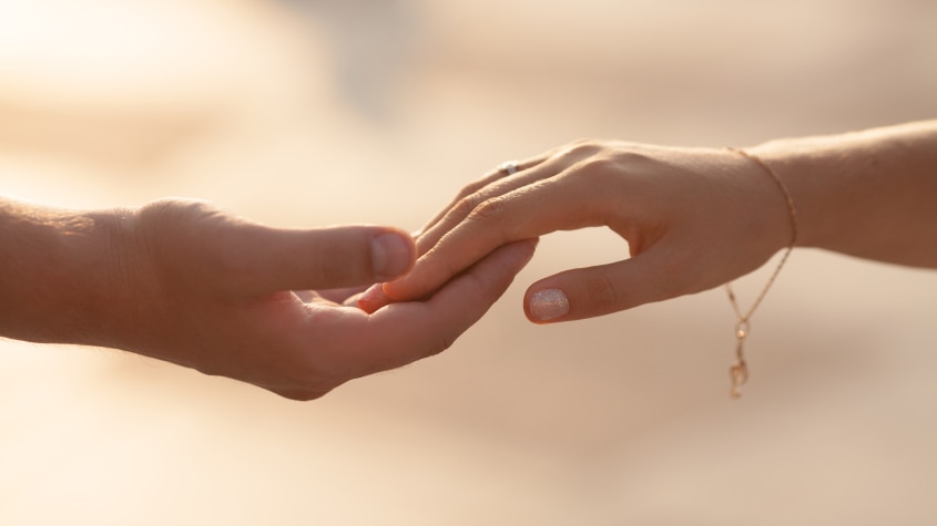 Man's hand reaching out to hold woman's hand