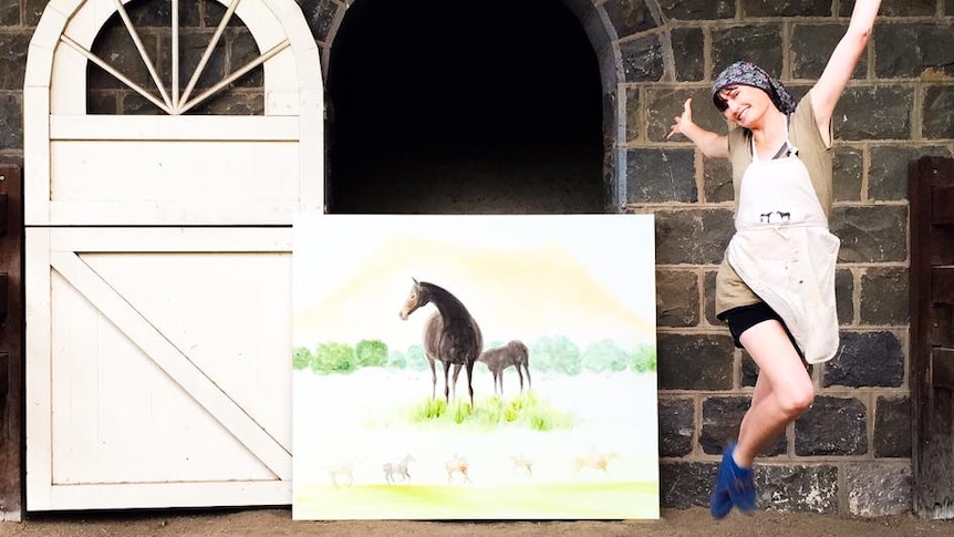 Laura Douglas poses with a piece in a horse stable