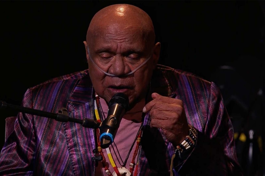 Archie Roach sings into a microphone