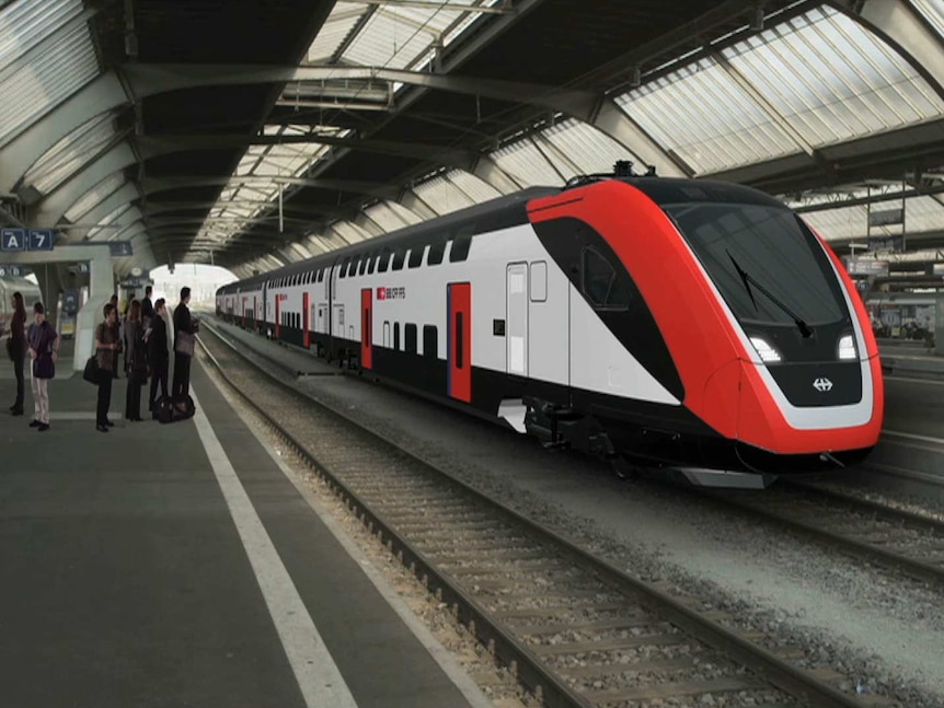 People wait on a platform as a train enters the station.