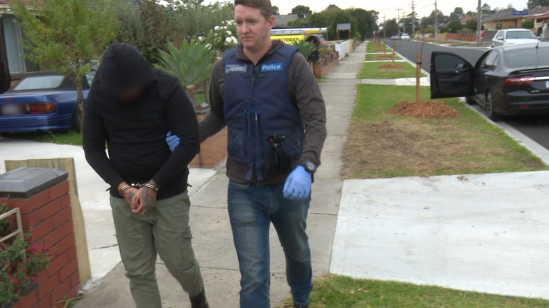 A Victoria Police officer takes away a man in handcuffs in Melbourne.