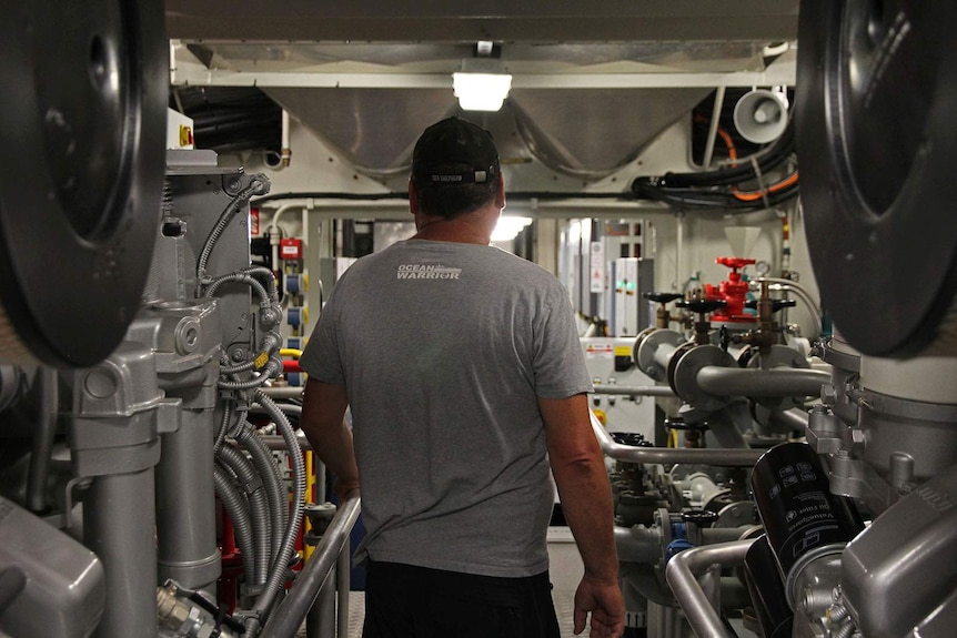 A man walks through the engine room of the Ocean Warrior ship.