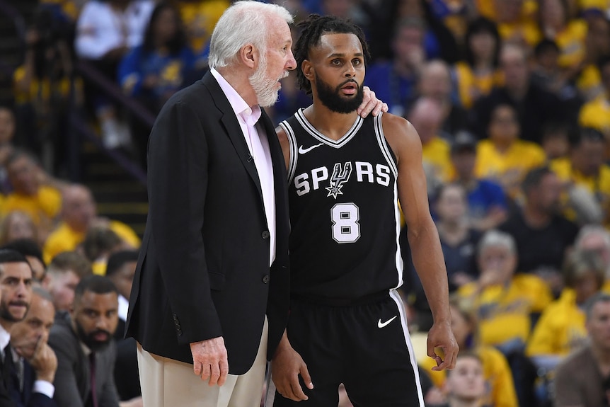 Gregg Popovich and Patty Mills chat on the court in 2018.