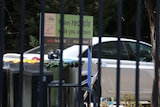 A car with police tape on it behind the gates at Manuka Oval in Canberra.