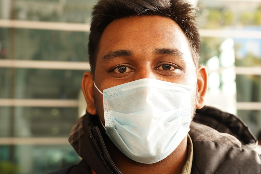 A close up shot of a young Indian man in a face mask 