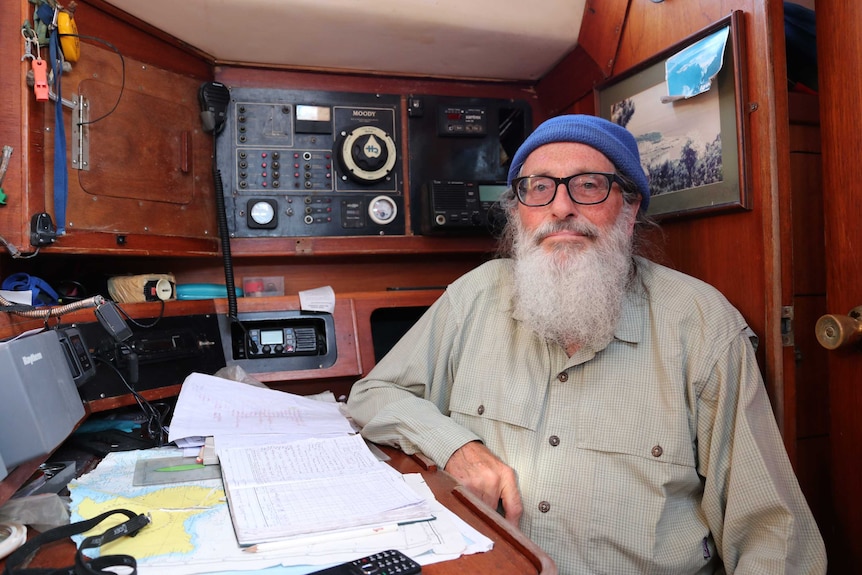 Man inside yacht cabin sitting at table on right communication gear on walls around him