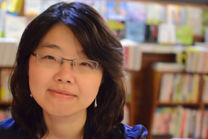 Headshot of woman with glasses smiling to camera.