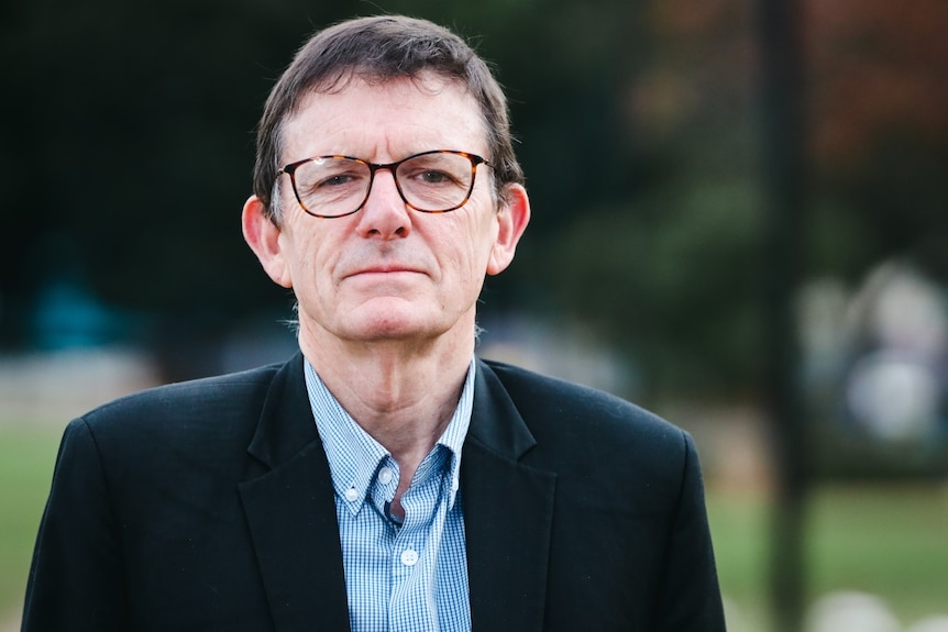 A man wearing glasses and a dark suit.