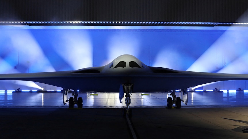 a stealth bomber is shown on a stage and is lit from behind 