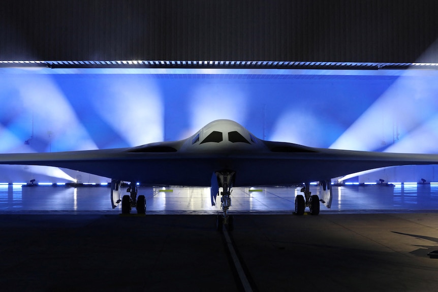 a stealth bomber is shown on a stage and is lit from behind 