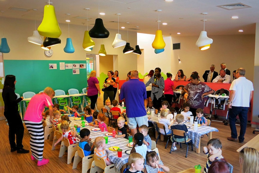 Parents and young children at tables in a large room.