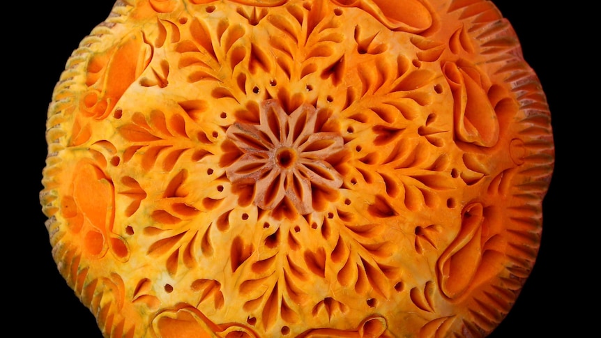 An intricate mandala carved from a pumpkin.