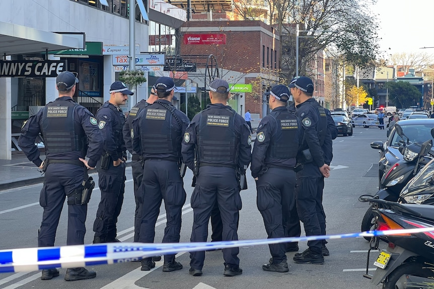 A group of heavily armoured police officers standing on a street