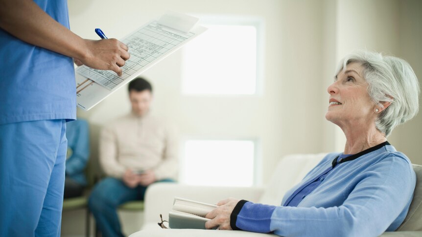A nurse hands a patient medical forms to complete