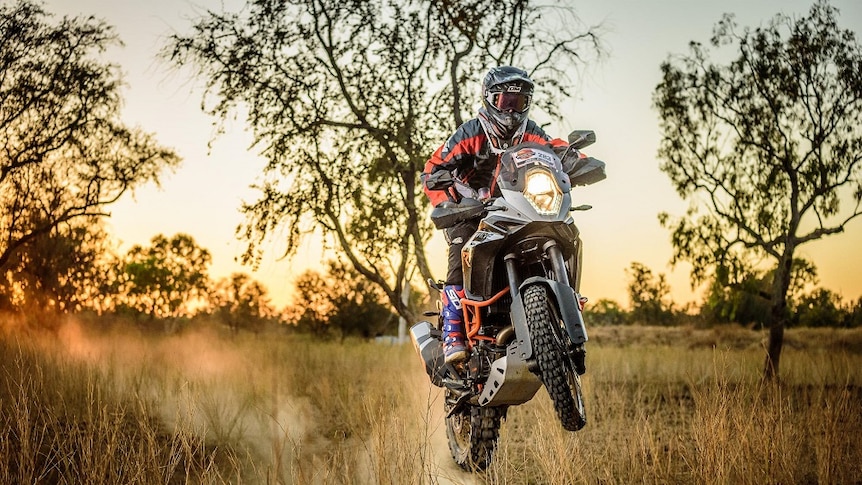 A motorbike rider travels through grassland
