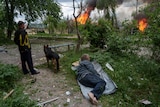 A man lies on the ground as he watches his burning house destroyed by a Russian airstrike in Vovchansk.