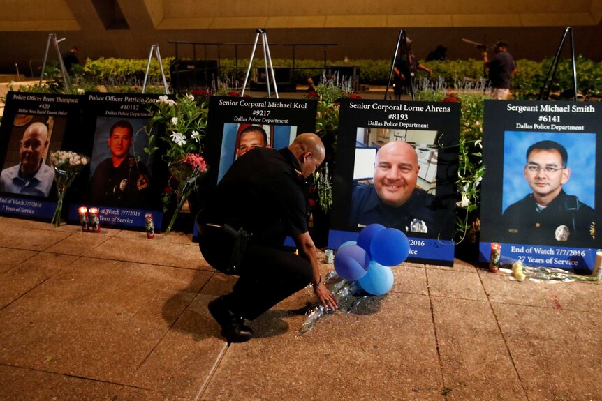 Images of five slain police officers are displayed at a memorial.