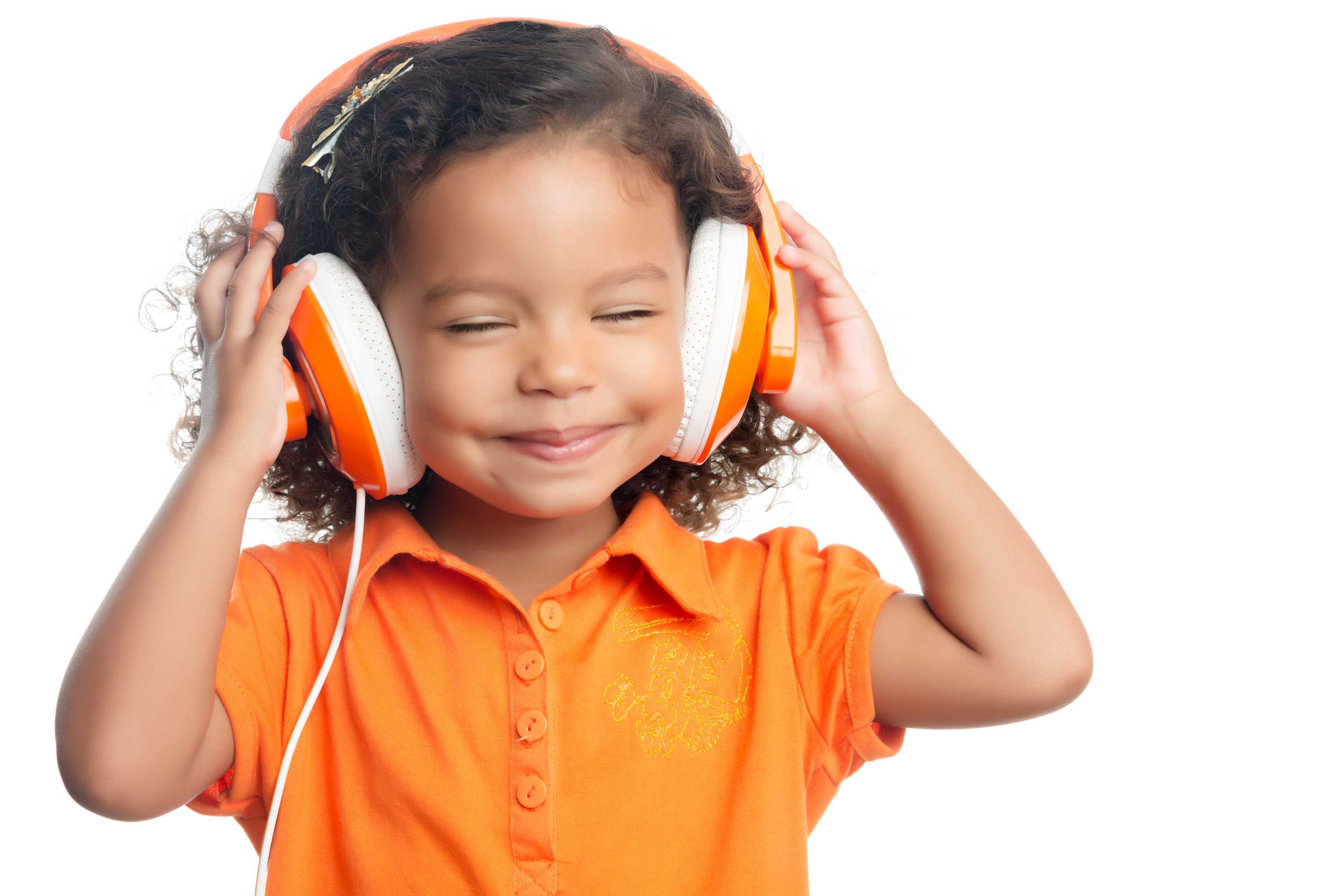 Young child wearing big orange headphones and smiling. 
