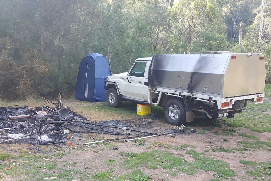 camping brûlé, avec tente brûlée, chaises et autres équipements de camping.  ute avec des dommages mineurs dus au feu.