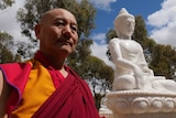 Geshe Rapten standing beside an aspect of the Buddha