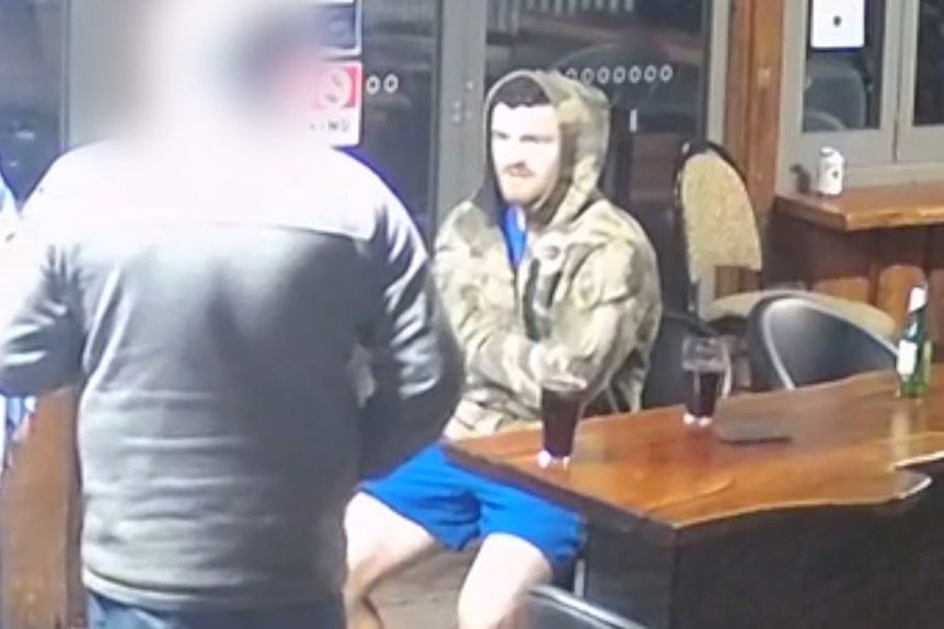 CCTV vision showing a man wearing a camoflague jacket sitting at a pub