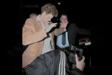 A paparazzi photographs Prince Harry at nighttime 