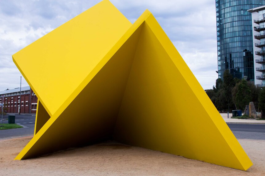 A large yellow sculpture consisting of several planes at angles with each other.