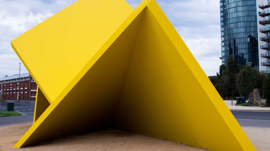 A large yellow sculpture consisting of several planes at angles with each other.