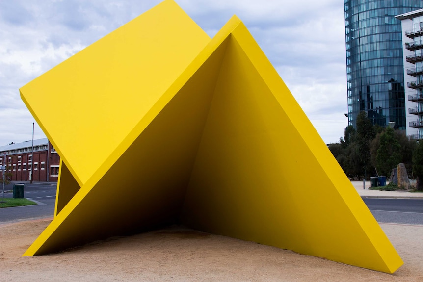 A large yellow sculpture consisting of several planes at angles with each other.