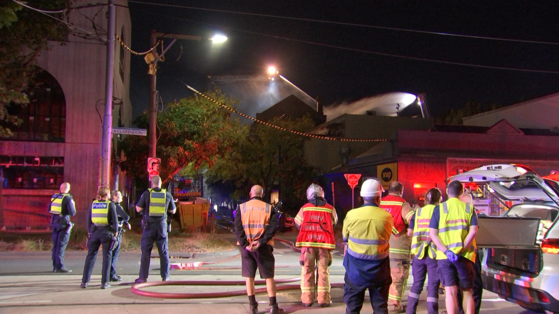 Firefighters and police near a burning building.
