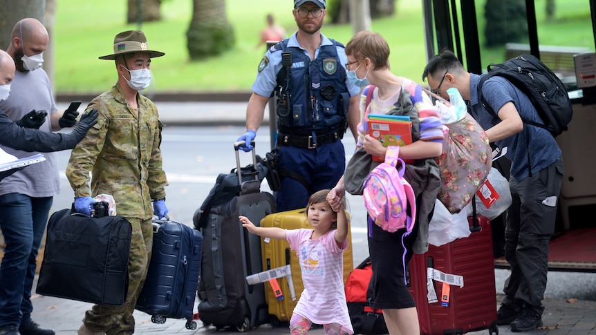 A young family disembark a bus with their luggage while a masked Australian soldier and policeman carry suitcases.