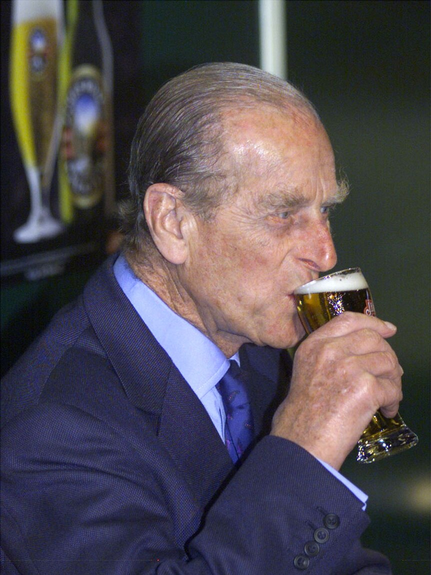 Prince Philip holding a glass of beer to his lips