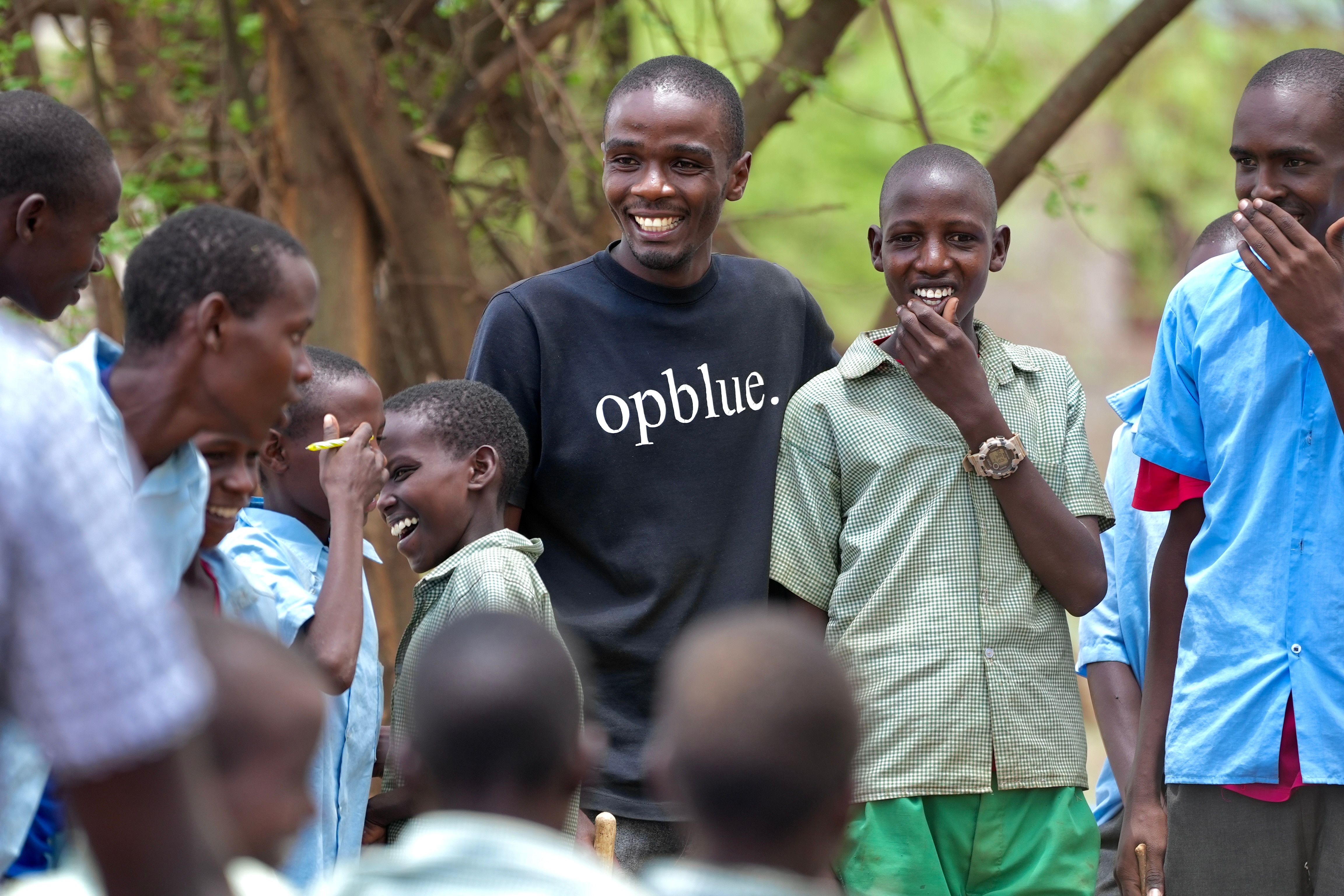 A group of school students and William Muchiru from OpBlue laughing and smiling.