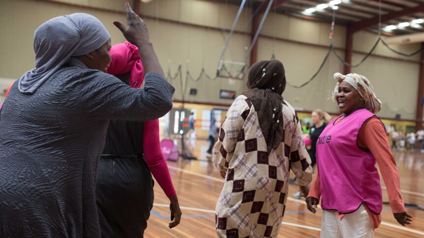 Entisar laughs as another woman waves her hand in the air during an indoor soccer match between Stand Up mums.
