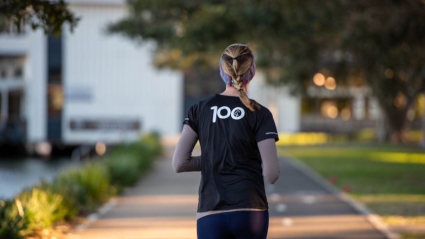 A woman runs along a footpath with her back to the camera.